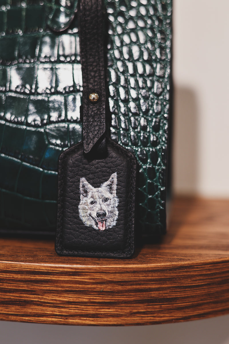 Hand-painted White German Shepherd portrait on a Strathberry leather luggage tag by Aivis Provejs, bespoke luxury leather personalisation.
