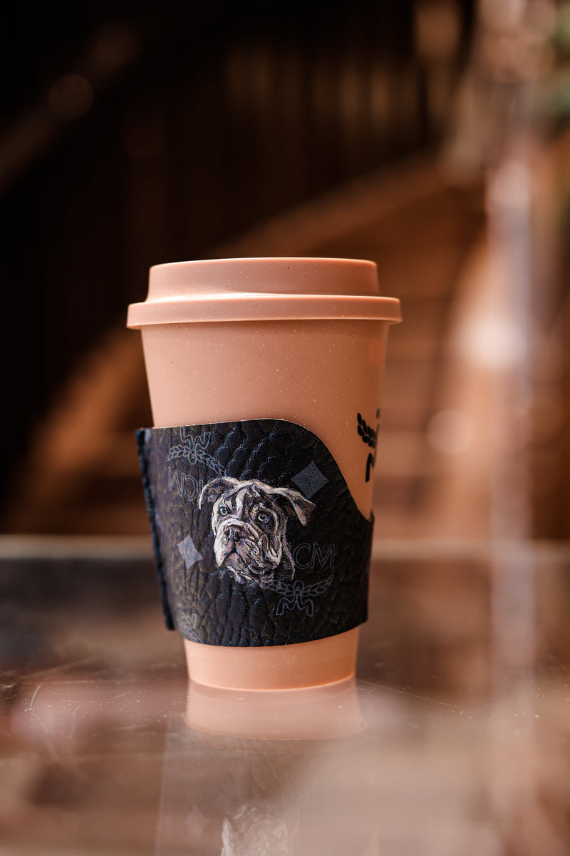 Hand-painted Pug dog portrait on an MCM leather coffee cup holder by Aivis Provejs, bespoke luxury leather personalisation and pet portrait artwork."