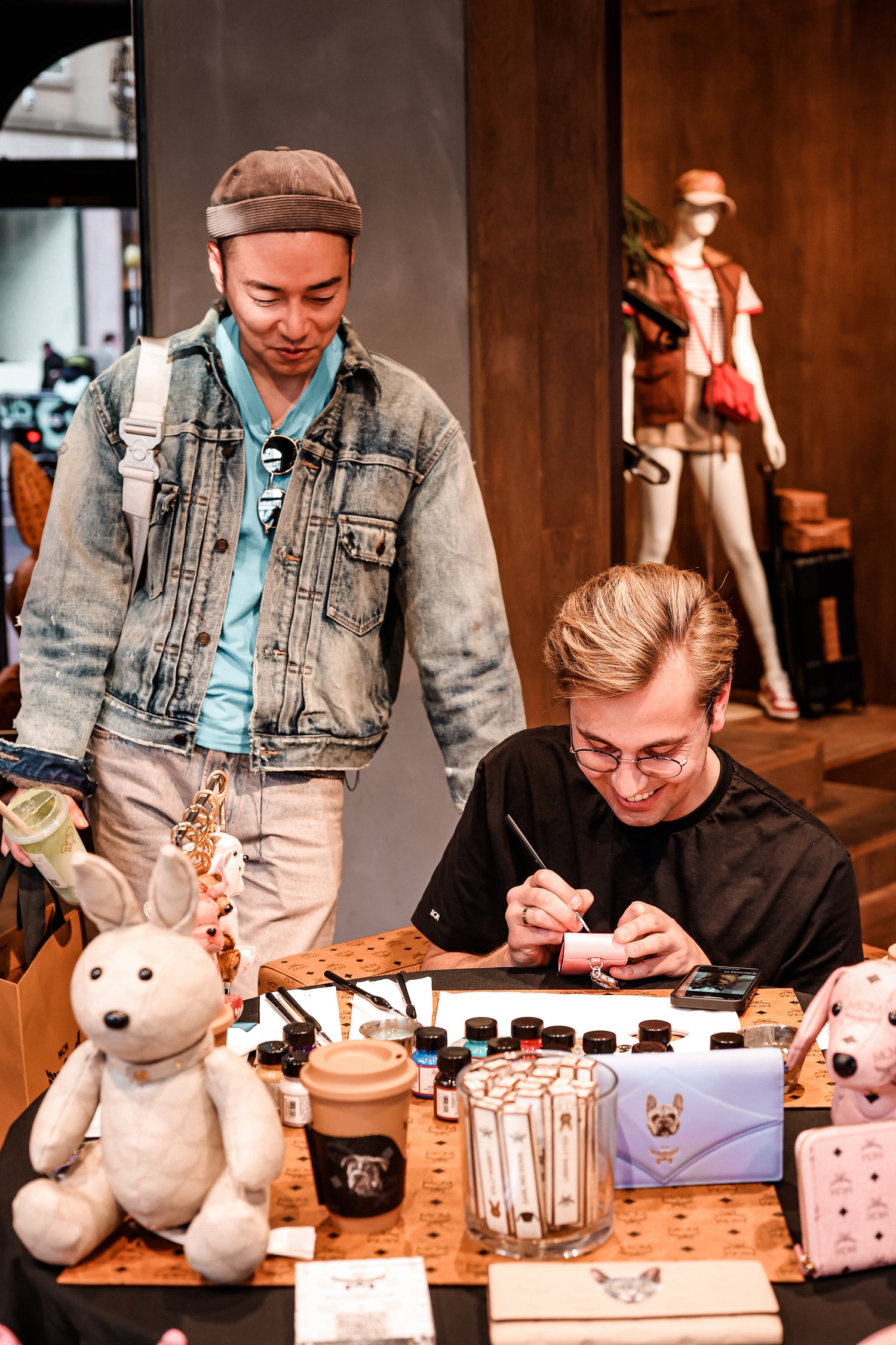 London artist Aivis Provejs hand-painting luxury leather accessories at a VIP shopping event
